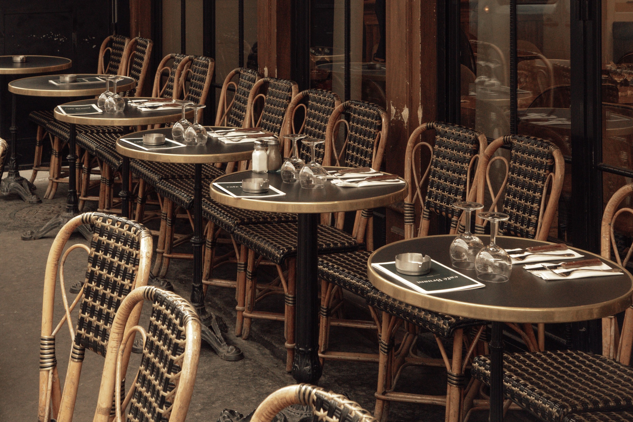 A Paris bistro terrace, tables laid, before service.