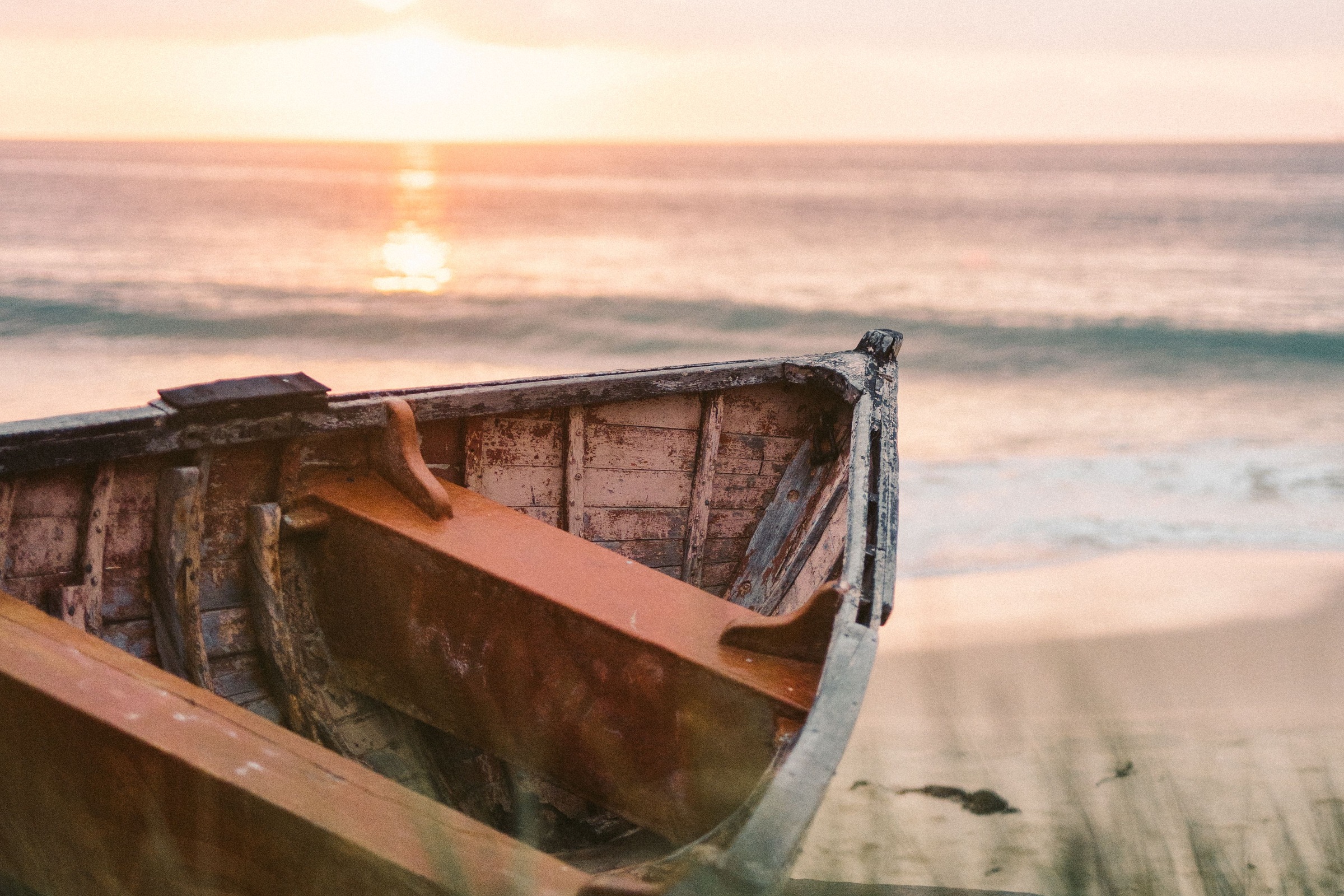 A fishing boat on a pale shore at dawn.