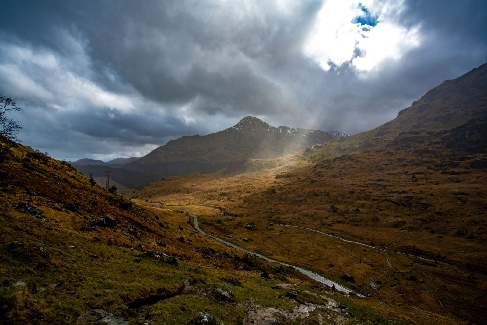 A single-track Highland road with weather coming in.