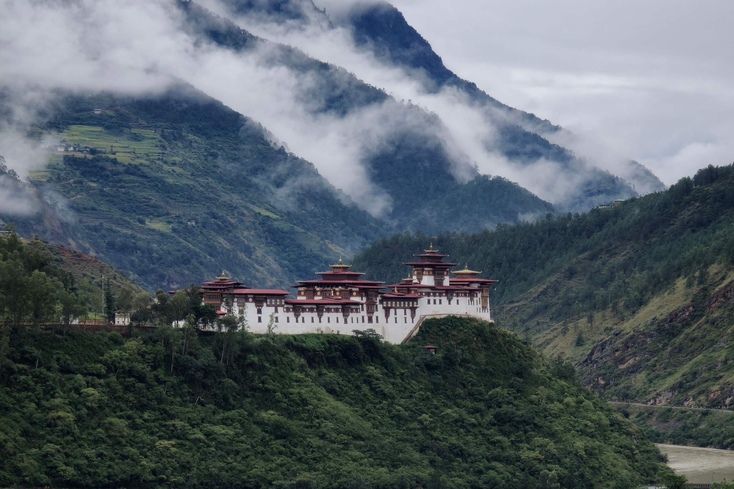 A fortress monastery above a river valley at morning.