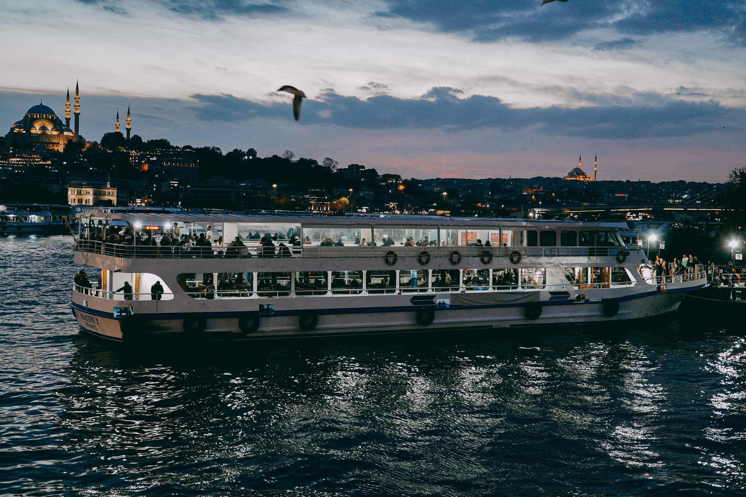 A ferry crossing between two shorelines at dusk.