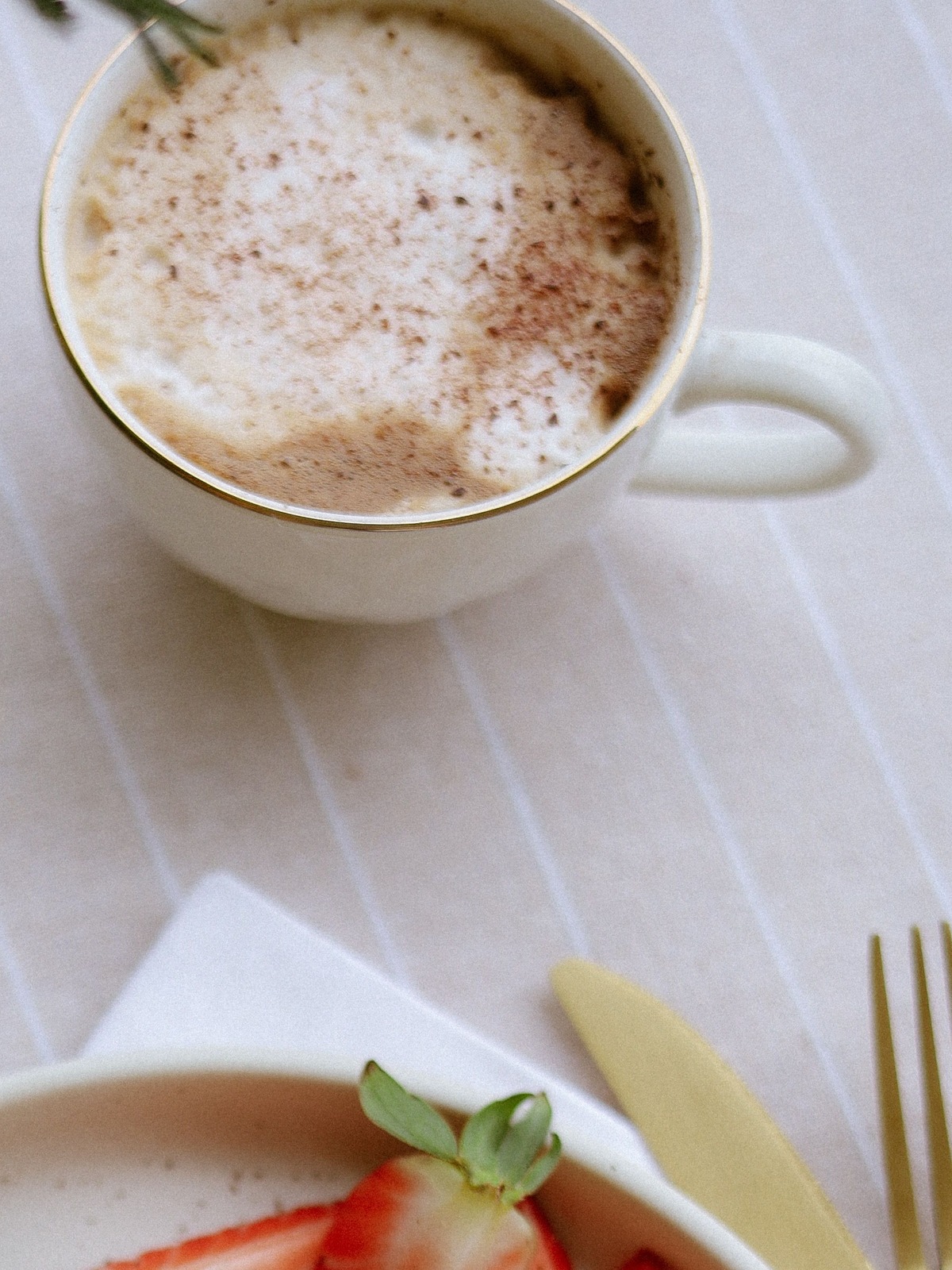 A cup of coffee on striped linen, morning light.